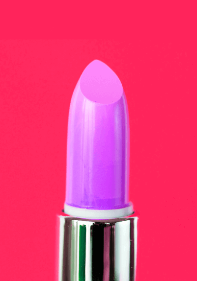 A close-up of a purple lipstick in a silver tube, set against a bright pink background.