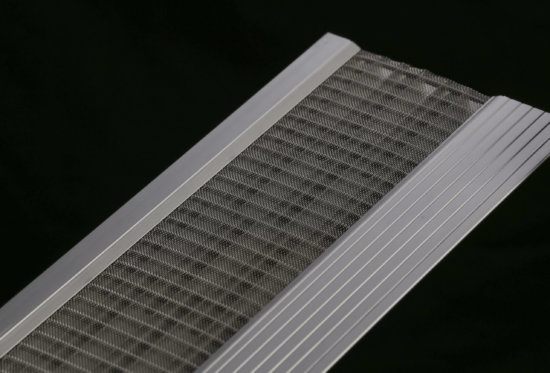 Close-up of a metal mesh filter with an aluminum frame, placed diagonally against a black background. The mesh is tightly woven and bordered by solid metal sides.