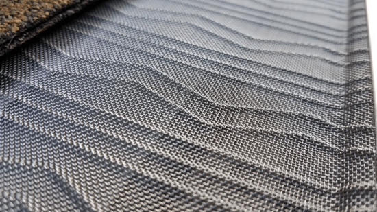 Close-up of a textured, black and gray woven fabric with a geometric, zigzag pattern, showing detailed threads and subtle variations in shading.